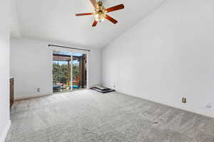 Spare room featuring light colored carpet, ceiling fan, and vaulted ceiling