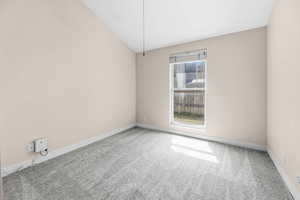 Spare room featuring lofted ceiling and light colored carpet