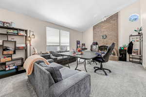 Carpeted office with vaulted ceiling and a fireplace
