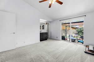 Unfurnished bedroom featuring access to outside, light carpet, lofted ceiling, a ceiling fan, and ensuite bathroom