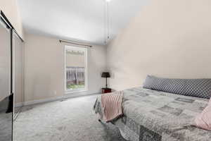 Bedroom with carpet, a closet, and vaulted ceiling