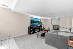 Living room featuring a glass covered fireplace, light tile patterned floors, and light colored carpet