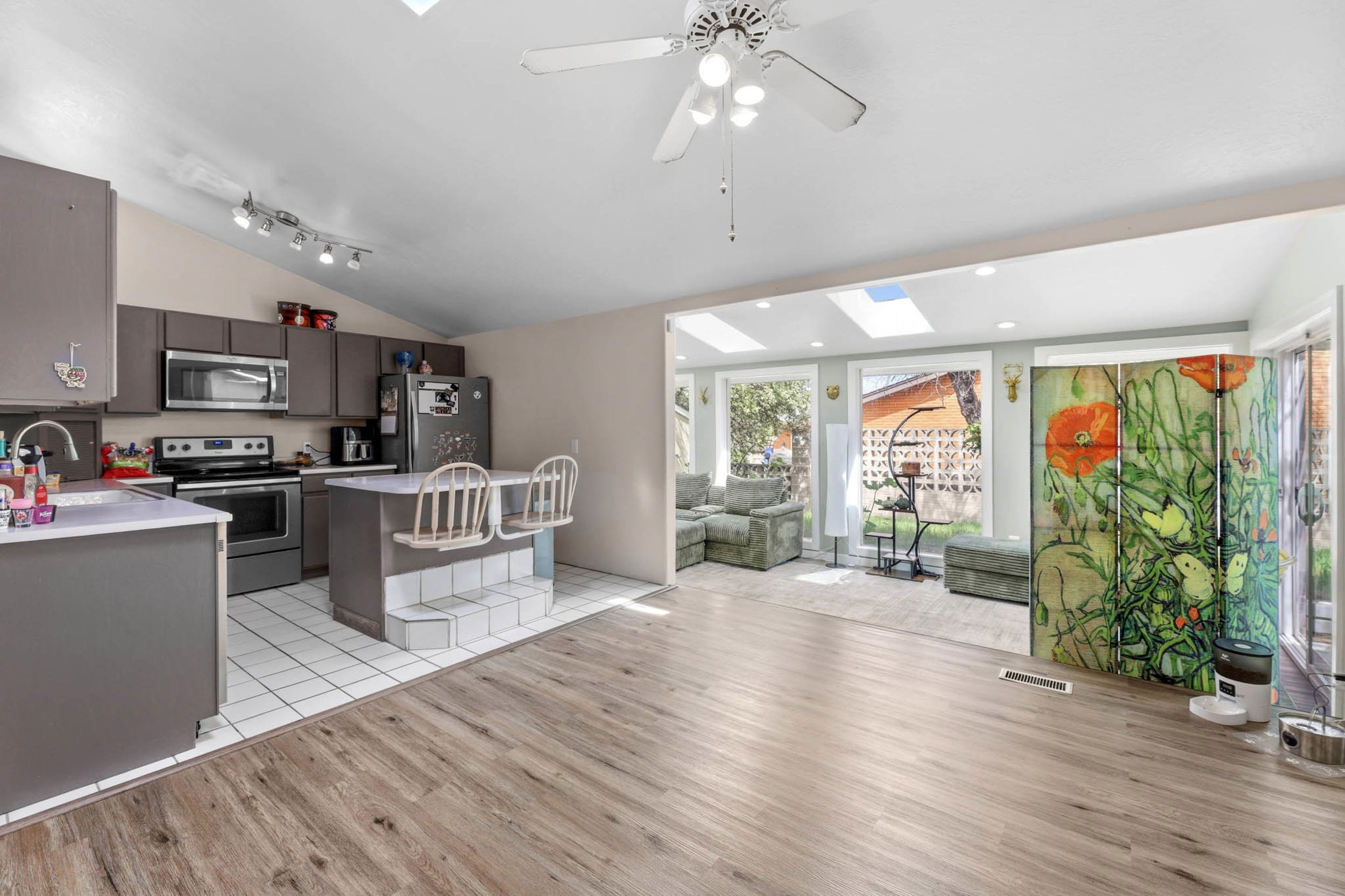Kitchen featuring a center island, stainless steel appliances, vaulted ceiling, light wood-type flooring, and light countertops