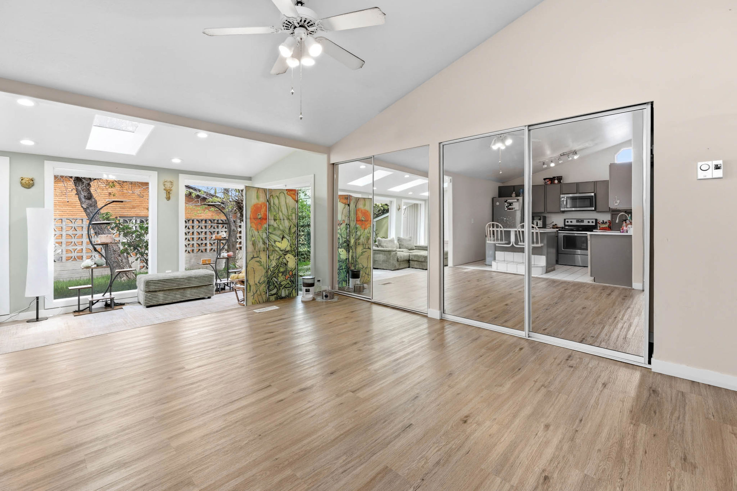 Unfurnished living room with light wood finished floors, vaulted ceiling, recessed lighting, ceiling fan, and a skylight