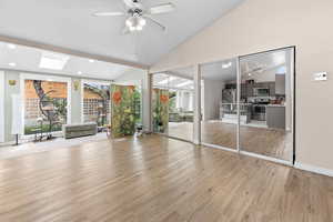 Unfurnished living room with light wood finished floors, vaulted ceiling, recessed lighting, ceiling fan, and a skylight