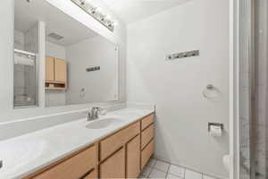 Full bathroom with a marble finish shower, vanity, and light tile patterned flooring