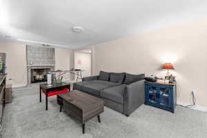 Living area featuring a tiled fireplace and light colored carpet