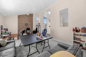 Rec room with carpet, vaulted ceiling, and a brick fireplace