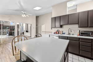 Kitchen with dark wood finish cabinets, light countertops, a kitchen breakfast bar, a kitchen island, and vaulted ceiling