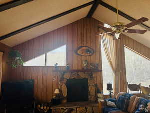 Living area featuringwood burning fireplace, large windows, and beam ceiling