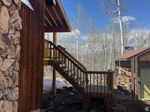 east side of cabin showing wooden deck with stairs, wood pile and east shed