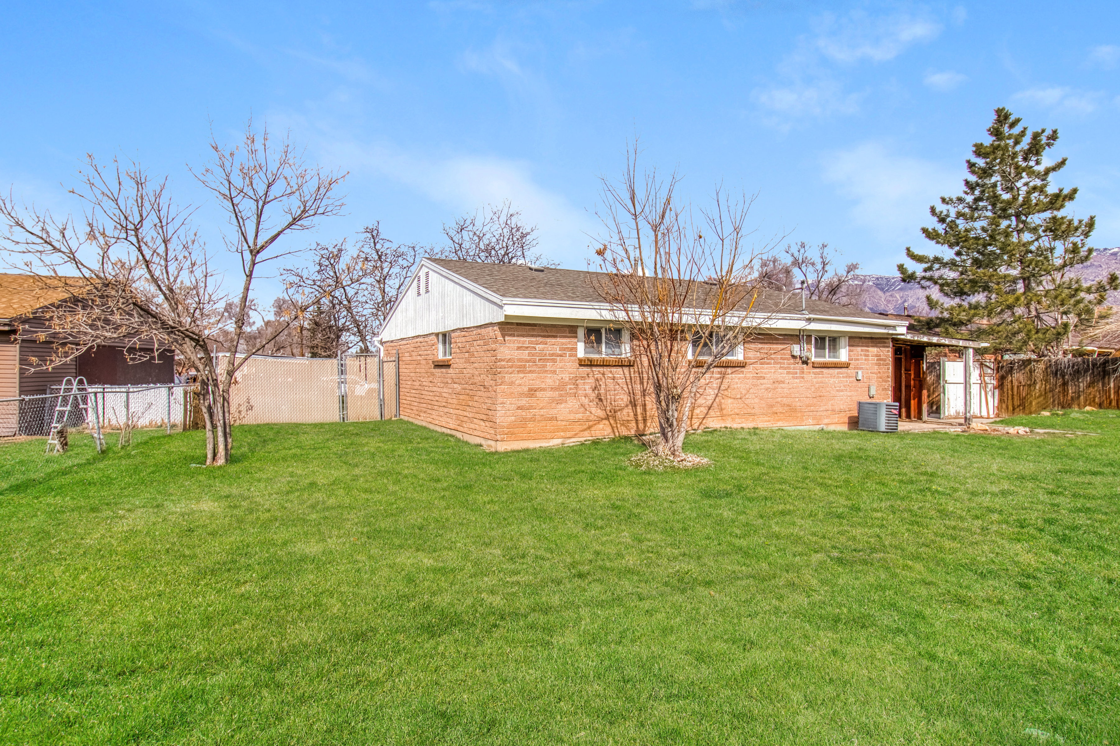 Rear view of property with a fenced backyard, brick siding, and a gate