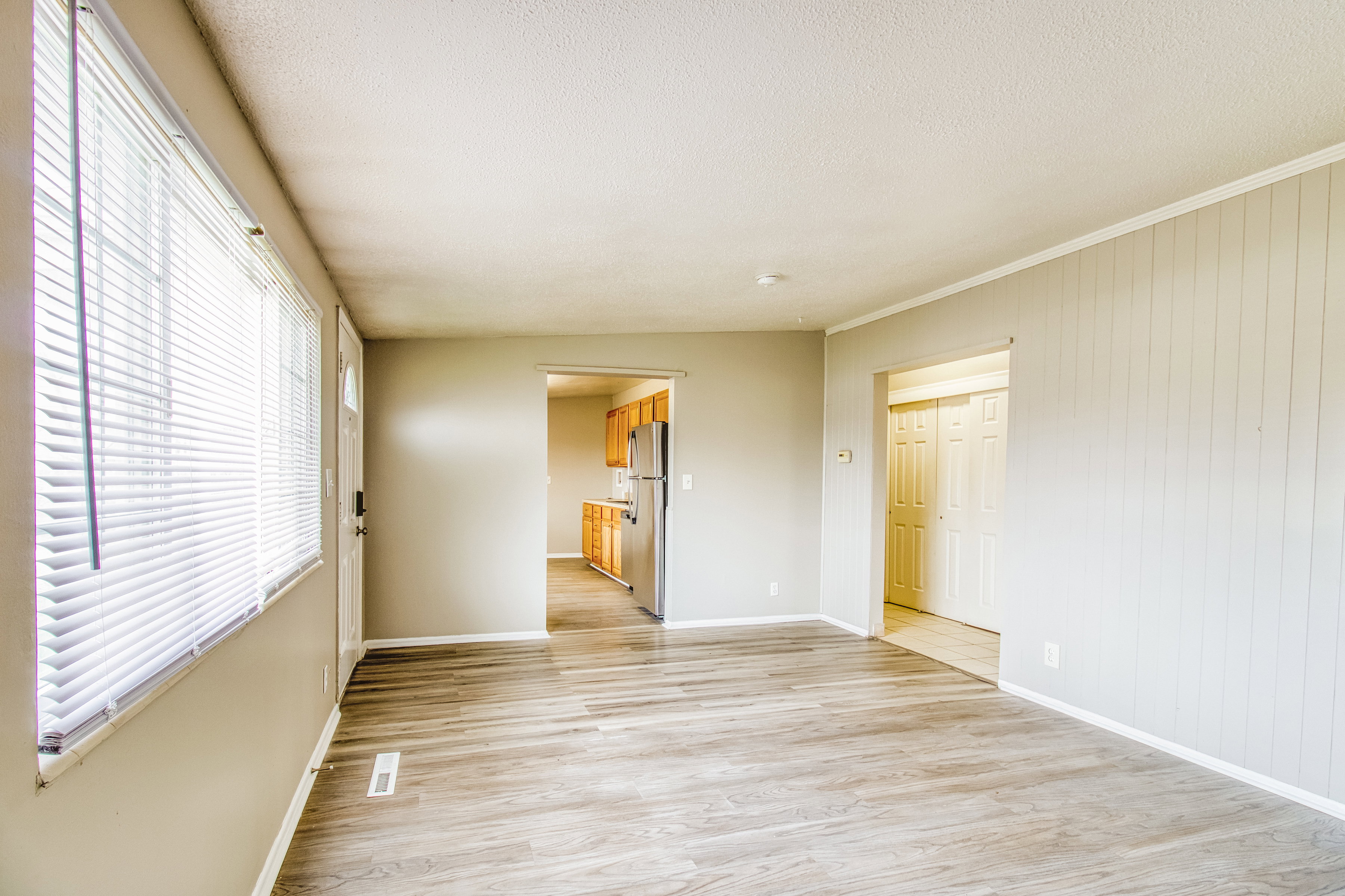 Unfurnished bedroom with light wood-style flooring, freestanding refrigerator, and a textured ceiling