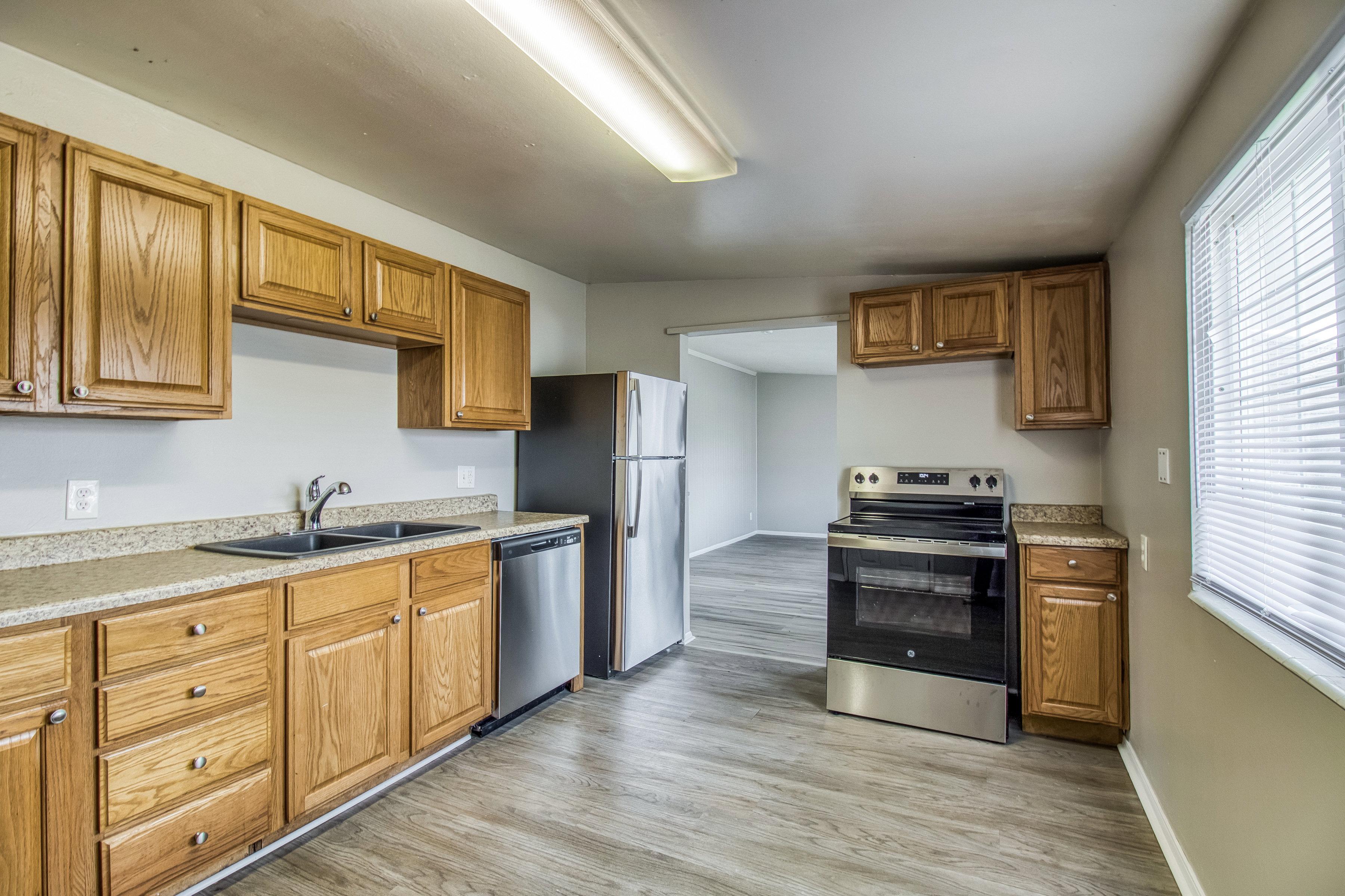 Kitchen featuring stainless steel appliances, wood finish cabinets, light countertops, and light wood-type flooring