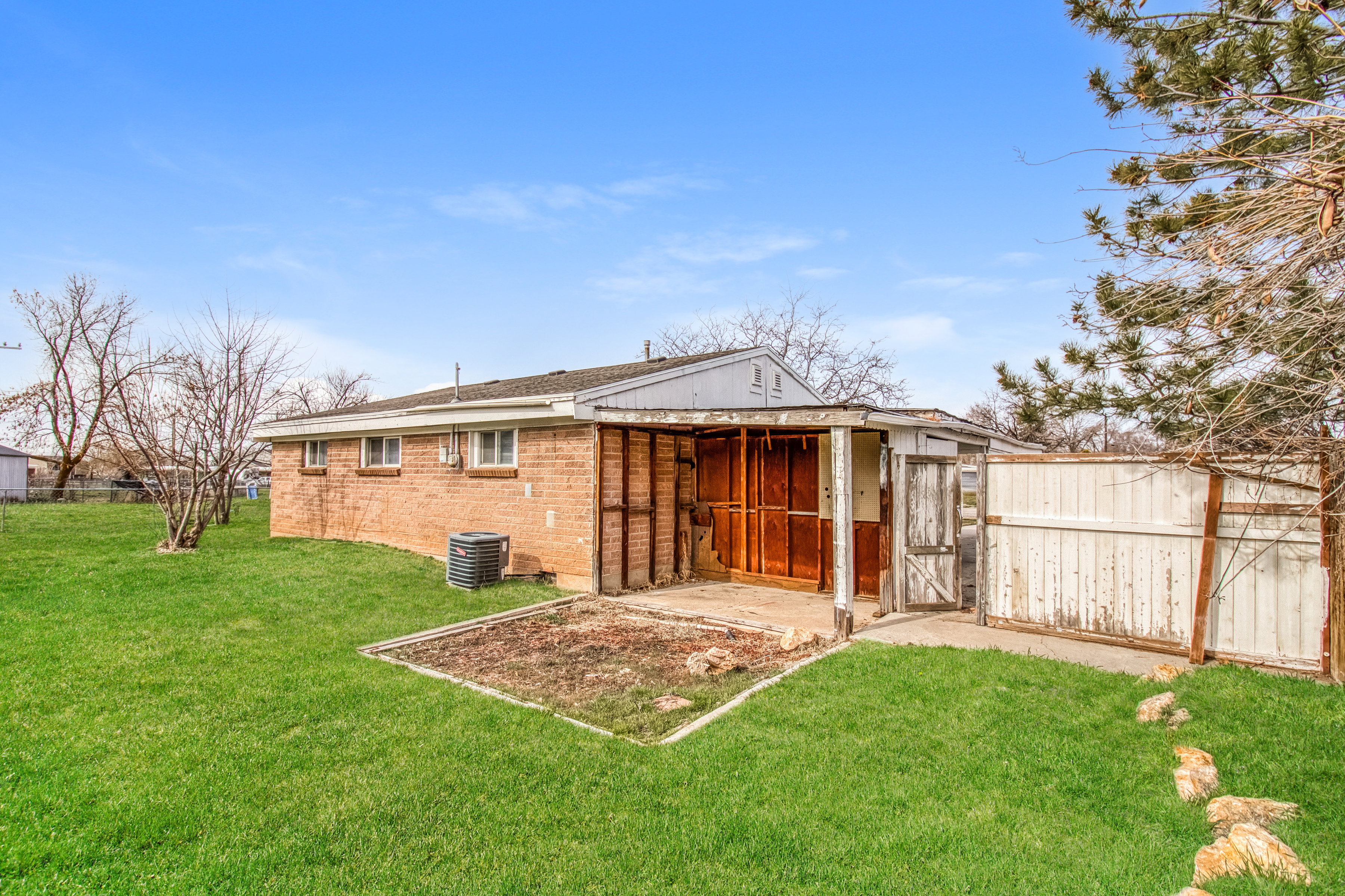 Back of property with brick siding, a patio, an outdoor structure, and roof with shingles