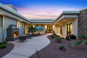 Property entrance featuring stucco siding, a patio, an outdoor living space with a fireplace, and french doors