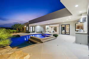 Relaxing pool / spa with french doors, an outdoor kitchen, and a patio area