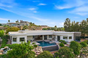 Rear view of house featuring a patio, stucco siding, a pool with connected hot tub, and stone siding