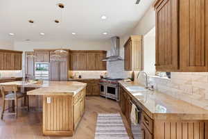 Kitchen featuring light stone countertops, a spacious island, light wood-style flooring, high quality appliances, and backsplash