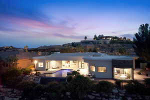 Back of property at dusk with stucco siding, a patio area, and an outdoor pool