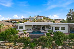 Back of property featuring stucco siding, a patio, stone siding, and a pool with connected hot tub
