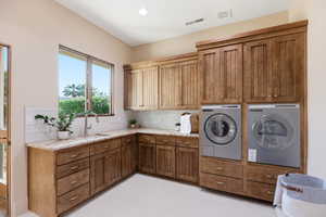 Laundry room with healthy amount of natural light, cabinet space, recessed lighting, and washing machine and dryer