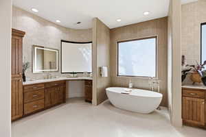 Bathroom with vanity, tile walls, a freestanding tub, and recessed lighting