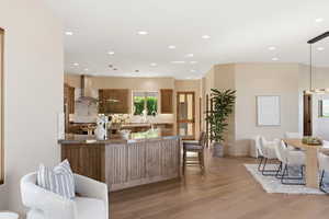 Kitchen featuring a breakfast bar area, hanging light fixtures, light wood-style floors, and wood finish cabinets