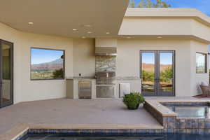 View of patio / terrace featuring exterior kitchen, a mountain view, french doors, and a pool with connected hot tub