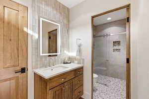 Full bath with decorative backsplash, vanity, and a shower stall