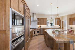 Kitchen featuring a kitchen island, wood finish cabinets, light wood-type flooring, and built in appliances