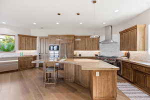 Kitchen featuring wood finish cabinets, light wood-style flooring, tasteful backsplash, and built in appliances
