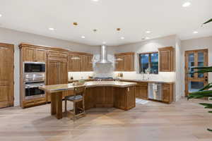 Kitchen featuring light wood-style flooring, wood finish cabinetry, stainless steel appliances, a center island, and pendant lighting