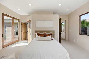 Bedroom with access to exterior, light colored carpet, and recessed lighting