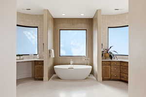Bathroom featuring vanity, tile walls, a freestanding bath, recessed lighting, and light tile patterned floors
