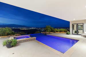 Pool at night with french doors, a pool with connected hot tub, a patio, and a mountain view