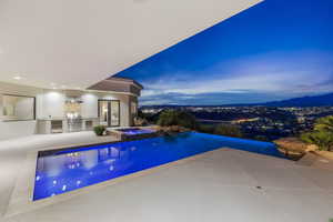 Integrated pool / spa featuring an outdoor kitchen and a patio