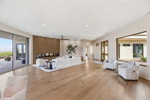 Living area featuring light wood finished floors, a ceiling fan, and recessed lighting
