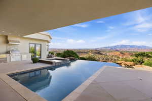 Integrated pool / spa with area for grilling, a mountain view, and a patio area
