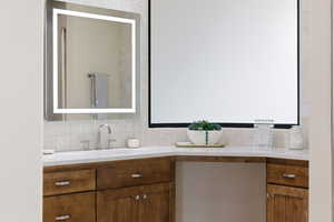 Bathroom featuring vanity and backsplash