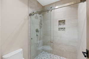 Full bath featuring toilet and a shower stall