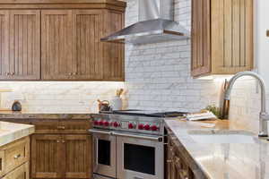 Kitchen with range with two ovens, light stone countertops, and tasteful backsplash