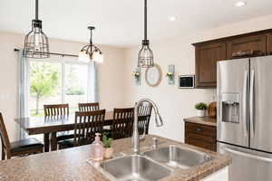 Kitchen featuring stainless steel fridge, dark wood finish cabinets, and a chandelier