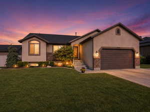Ranch-style home featuring an attached garage, brick siding, concrete driveway, stucco siding, and a front lawn