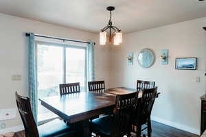 Dining area featuring dark wood-style floors and a chandelier & sliding door to backyard