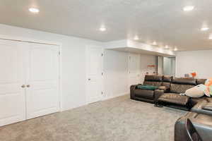 Living area featuring carpet floors, recessed lighting, and a textured ceiling