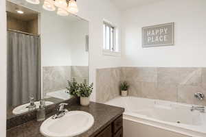 Full master bathroom with a tub with jets, vanity, and a shower with shower curtain