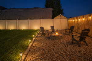 Yard at night with a fenced backyard and a fire pit - (Photo is Staged)