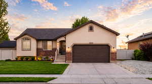 View of front facade with an attached garage, brick siding, stucco siding, and driveway & RV parking