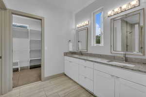 Full bathroom featuring a walk in closet, double vanity, and a shower